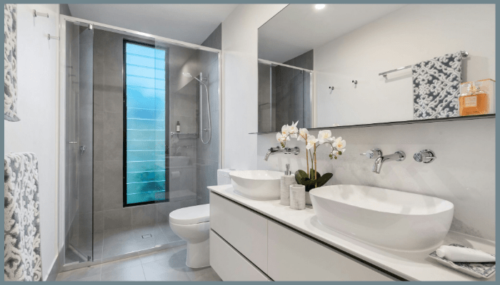 Stylish Canberra bathroom featuring a frameless glass shower, dual basins, neutral tones, and minimalist design with natural light.