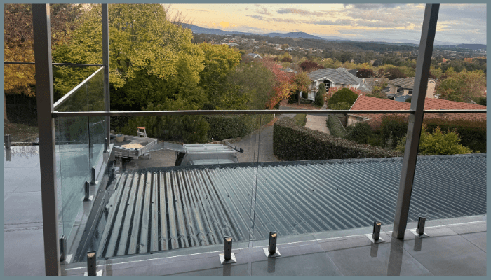 Standoff glass balustrade installation in progress on a Canberra balcony overlooking suburban and mountain views.