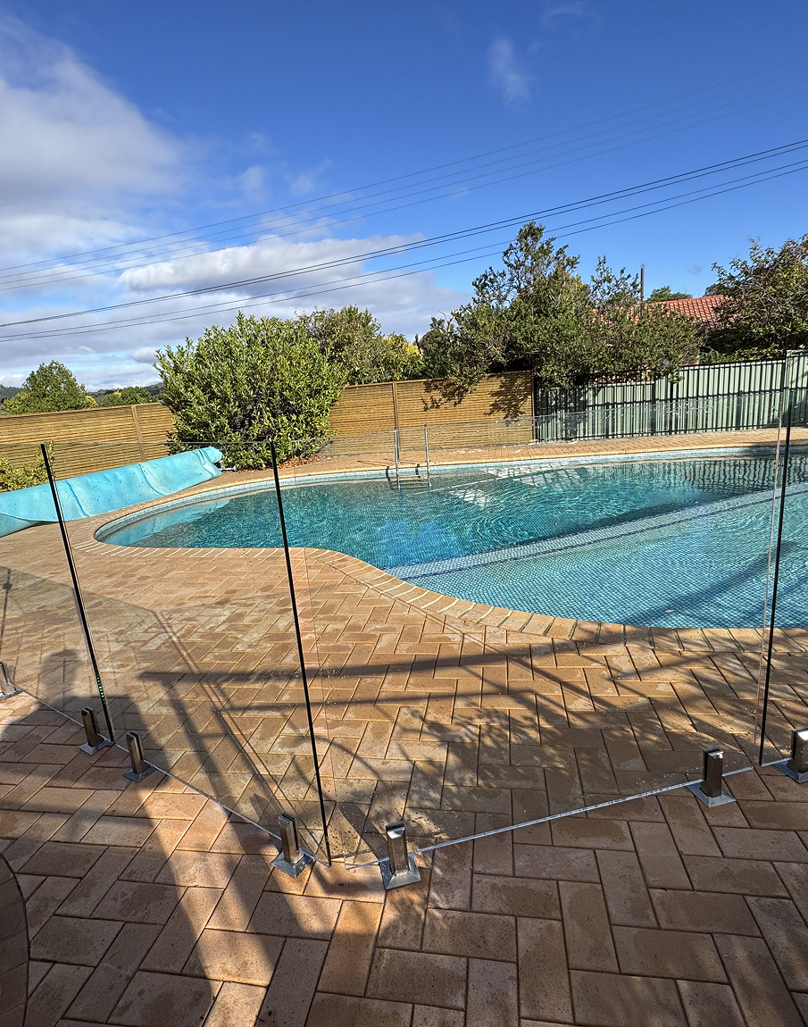 A large swimming pool surrounded by a glass fence.