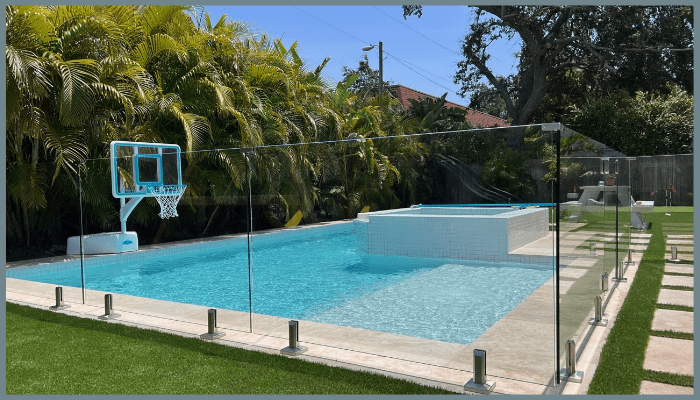 Backyard pool in Canberra with frameless glass fencing, creating a modern, seamless design with clear views of the landscape