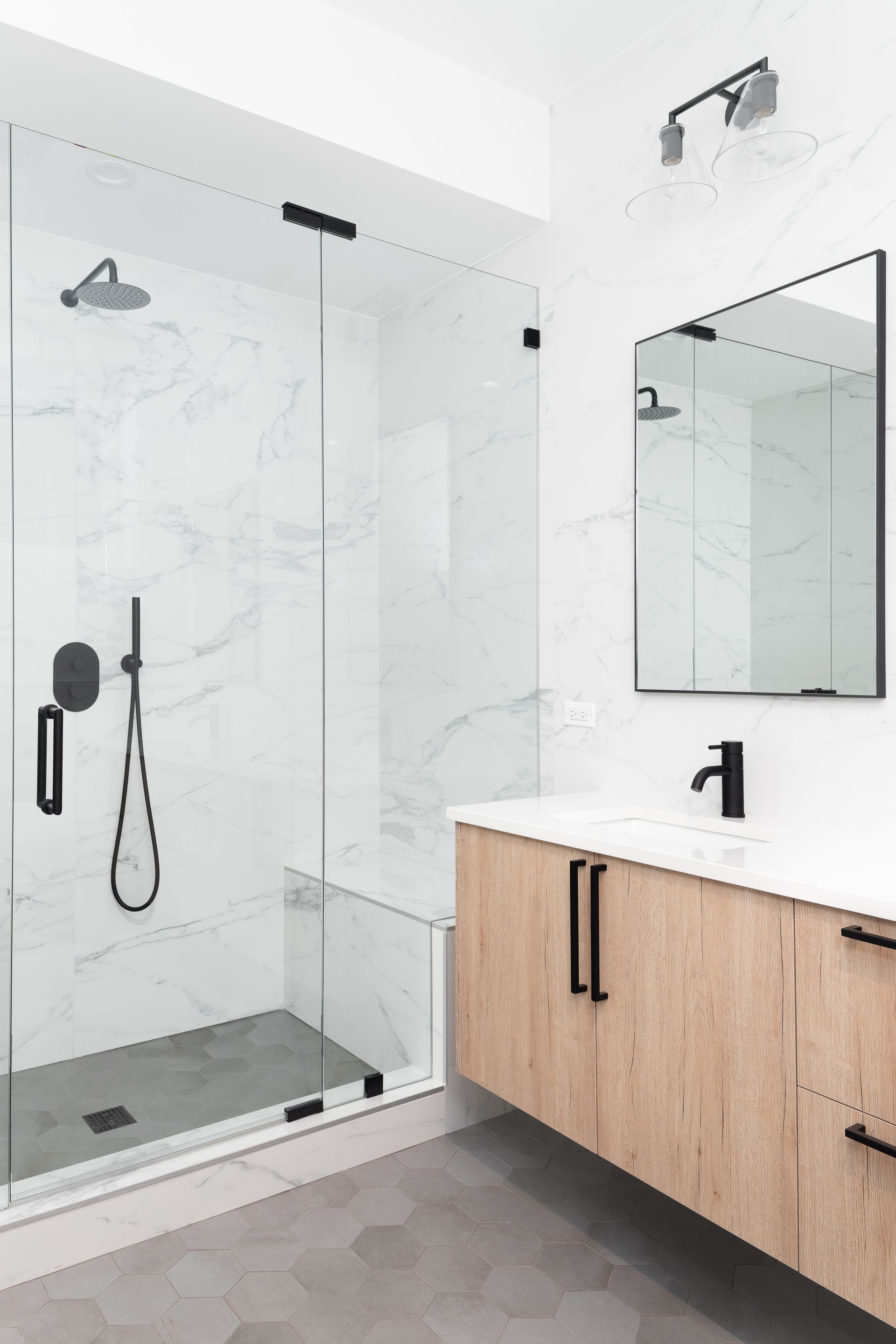 A bathroom with a walk in shower , sink and mirror.