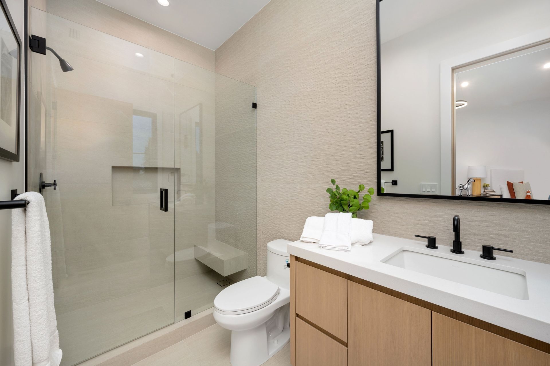 A bathroom with a walk in shower , sink and mirror.