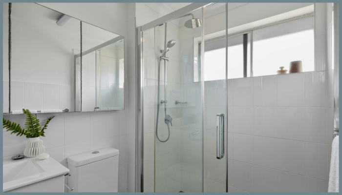 Sliding glass shower door in a modern bathroom with chrome hardware.