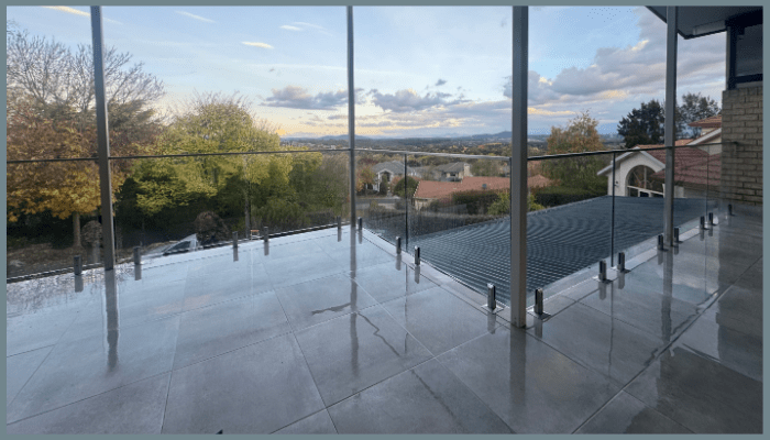 Newly installed standoff glass balustrade on a Canberra balcony with panoramic suburban and mountain views.