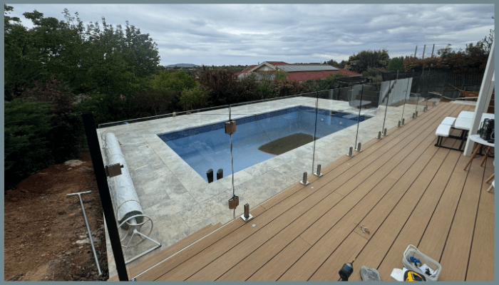 Close view of tempered glass pool fence panels secured with stainless steel spigots in Canberra