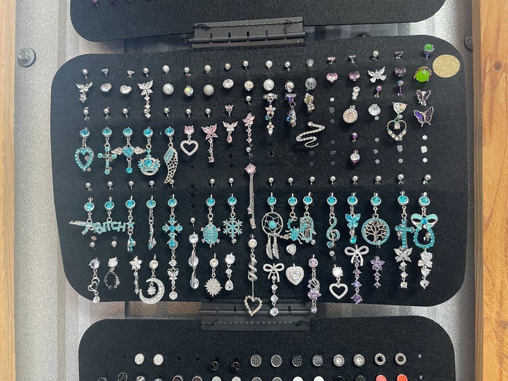 Display case of dangling earrings in silver, turquoise, pink, and black on black velvet trays