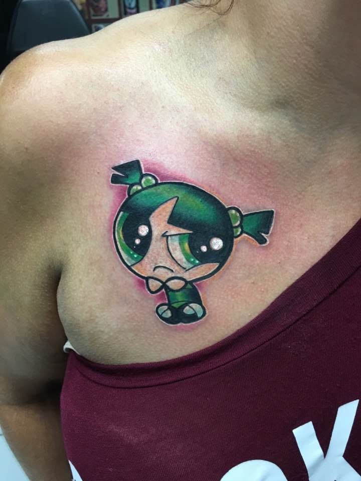 Cartoon Powerpuff Girls tattoo on a shoulder, featuring a green-haired character in black and green.