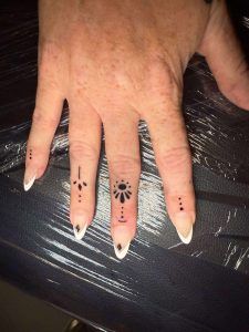 Hand with long white-and-black manicure and paw-print nail art on a dark striped surface