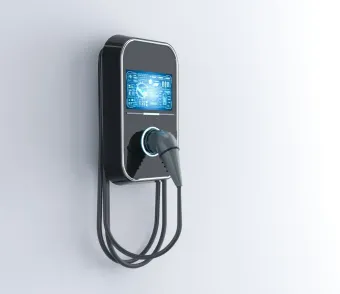 A black electric car charger is mounted on a white wall.