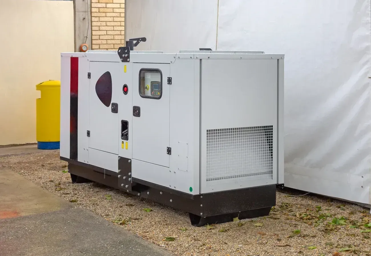 A large white generator is parked in front of a building.