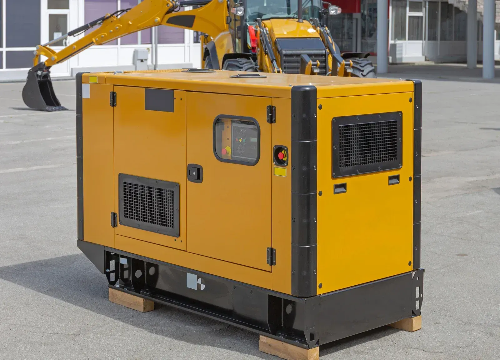 A yellow generator is sitting on a wooden pallet next to a bulldozer.
