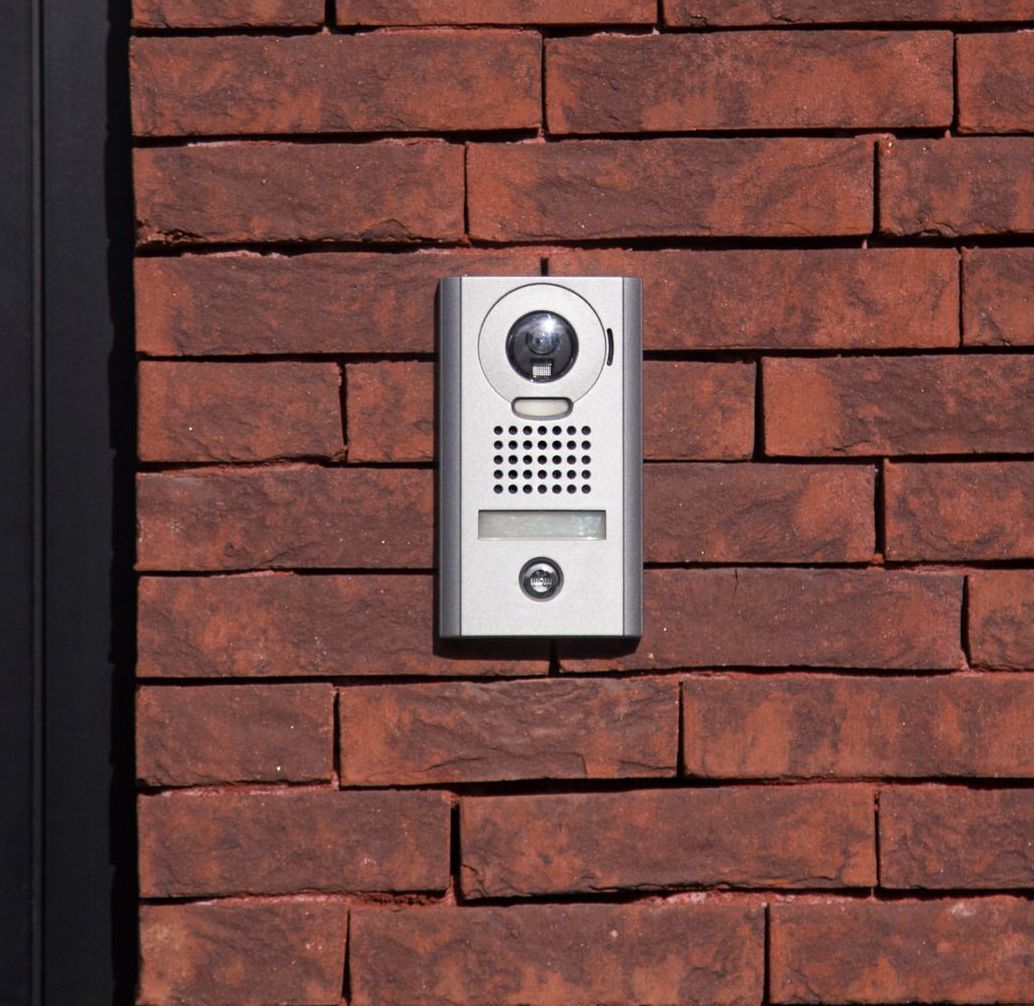 A doorbell is mounted on a red brick wall