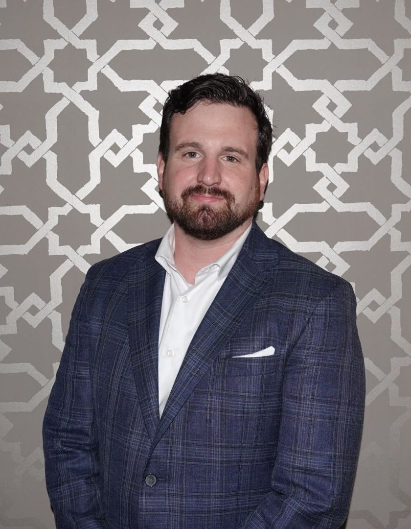 A man with a beard wearing a blue suit and white shirt