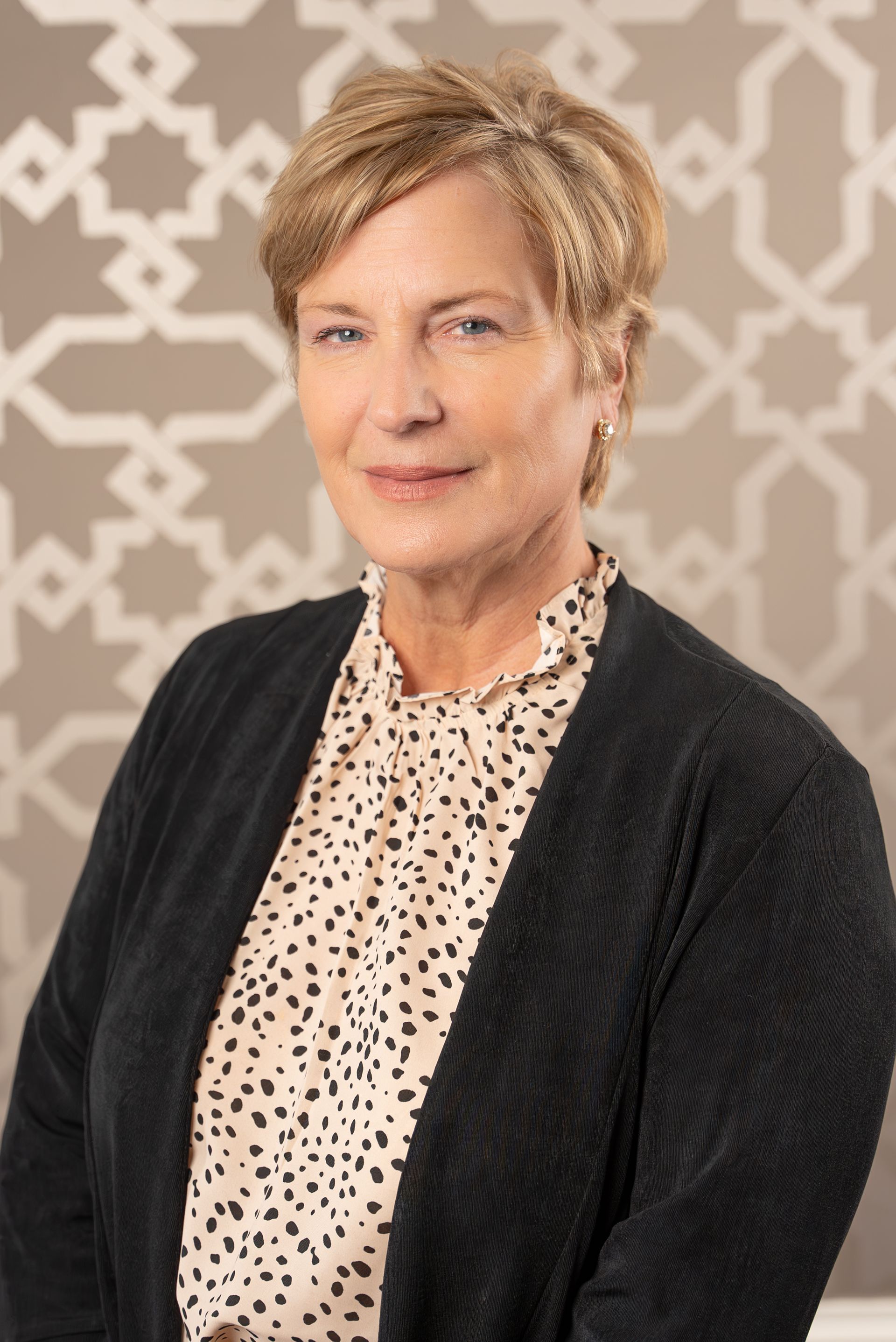 A woman is wearing a black cardigan and a polka dot shirt.