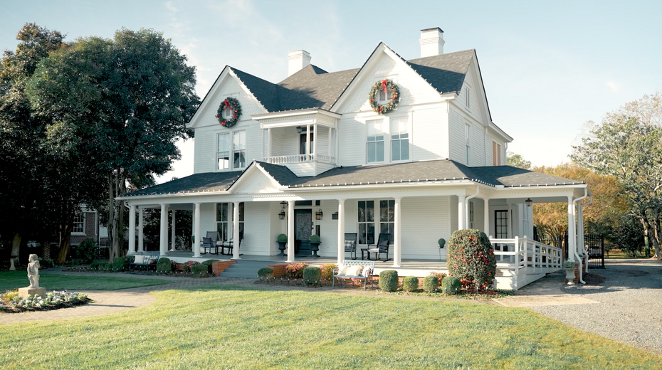 A large white house with a wreath on the front porch