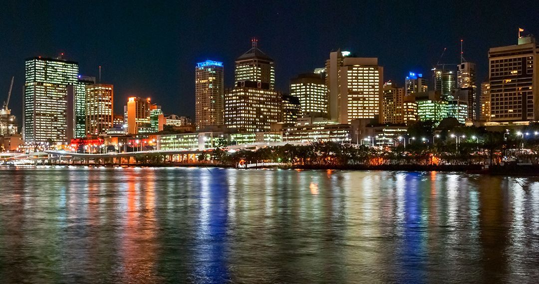 A City Skyline Is Reflected In The Water At Night — Queensland Lawyers Cairns In Brisbane, QLD