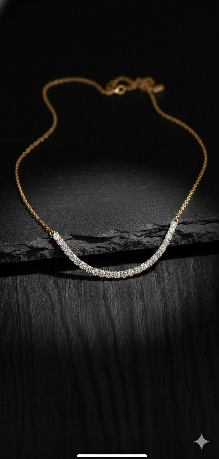 Gold necklace with a curved bar of white stones. On a dark, textured background.