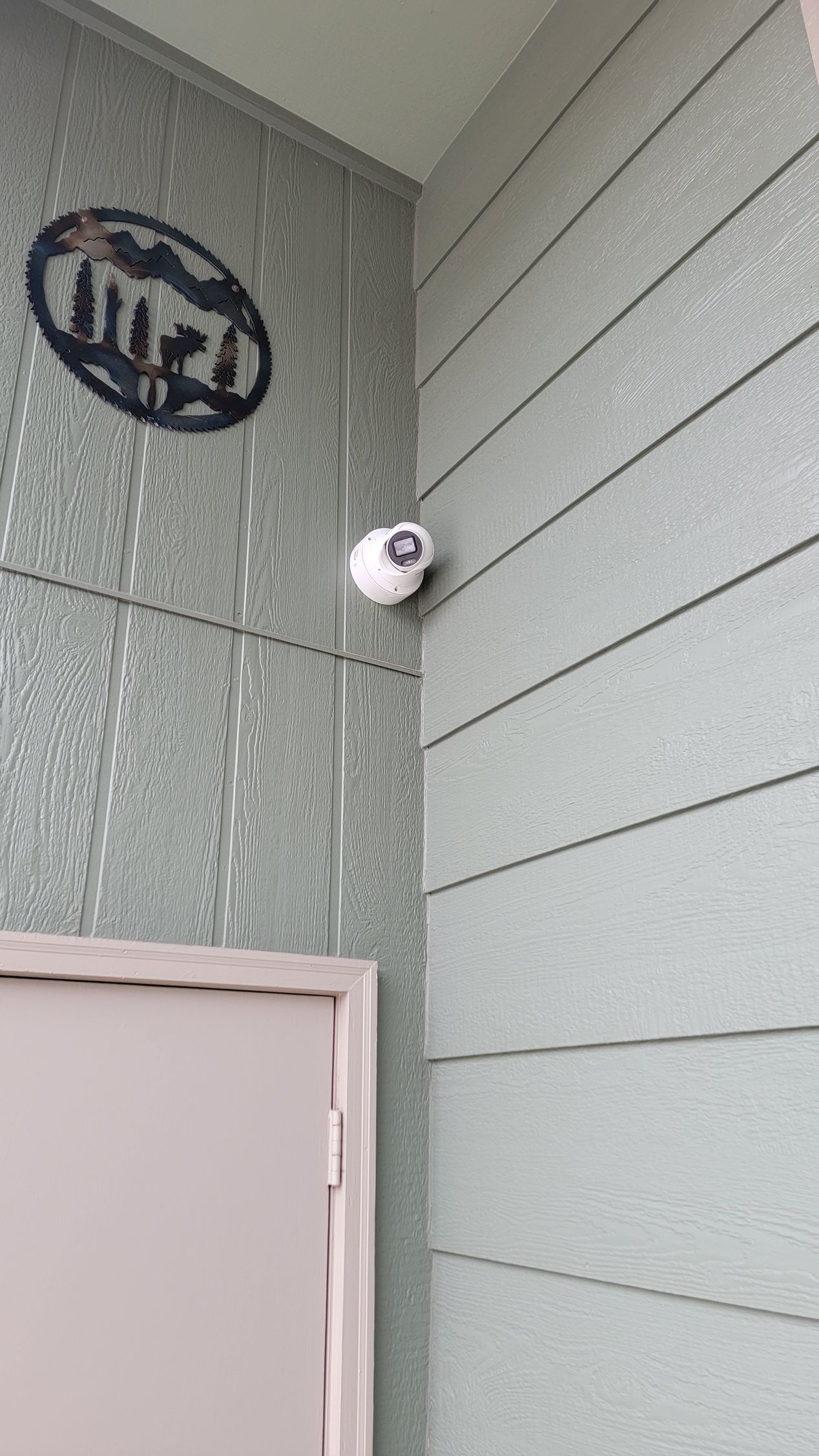 A security camera is mounted on a wall next to a staircase.