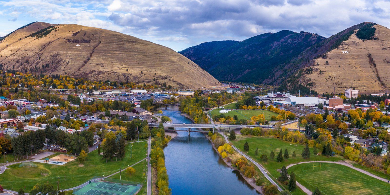 An aerial view of a city and a river with mountains in the background.