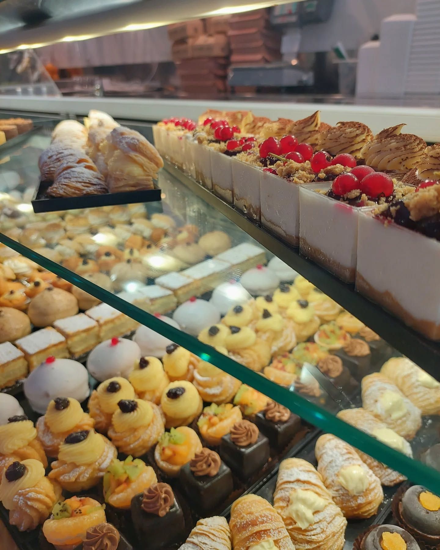 Pasticcini esposti in una vetrina di una pasticceria. File di dessert con guarnizioni diverse.
