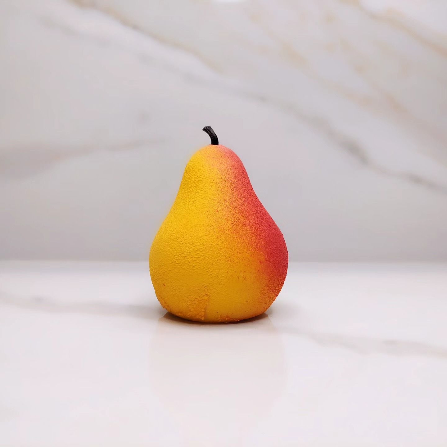 Pera gialla e rossa su una superficie di marmo bianco.