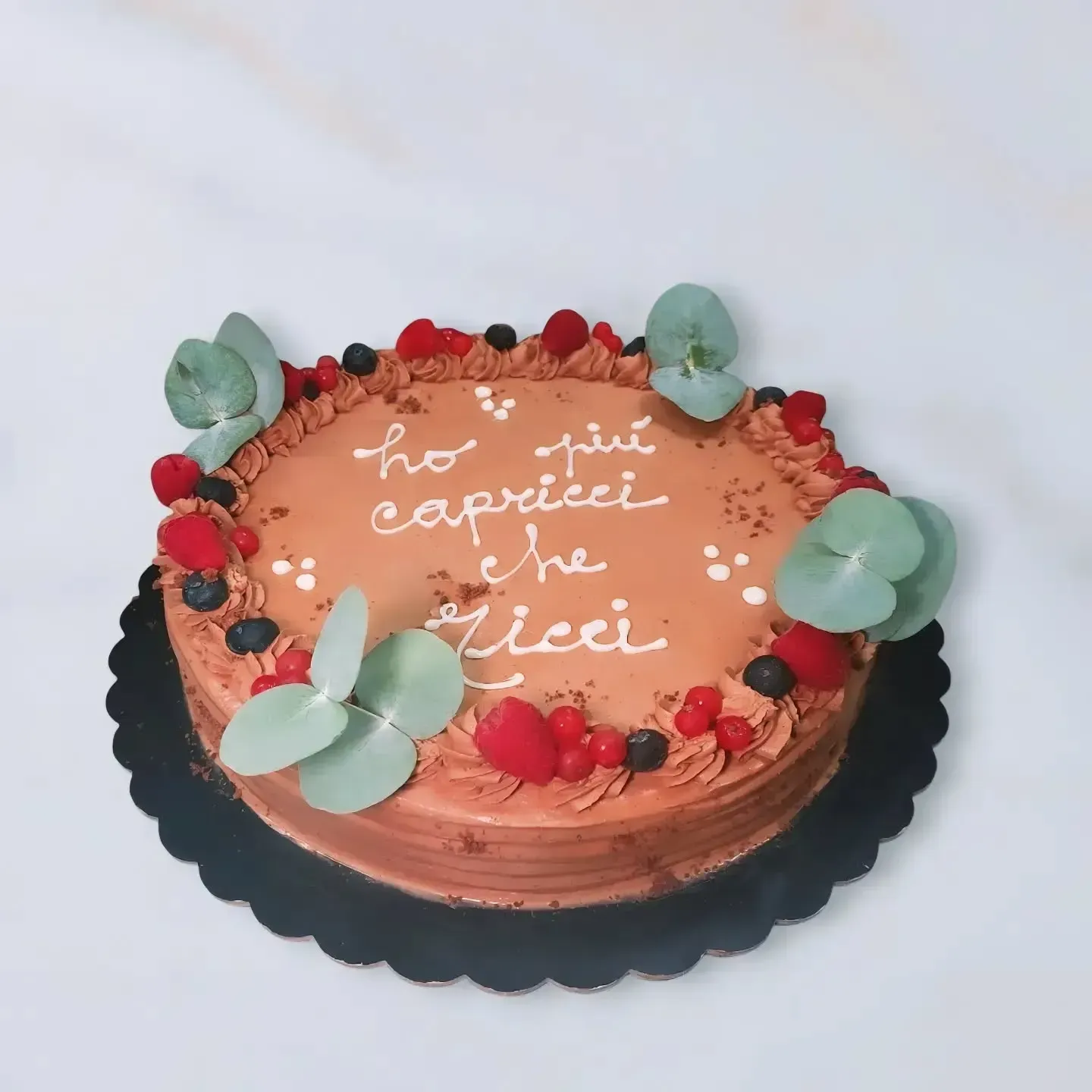 Torta al cioccolato con glassa alla panna, frutti di bosco, rametti di eucalipto