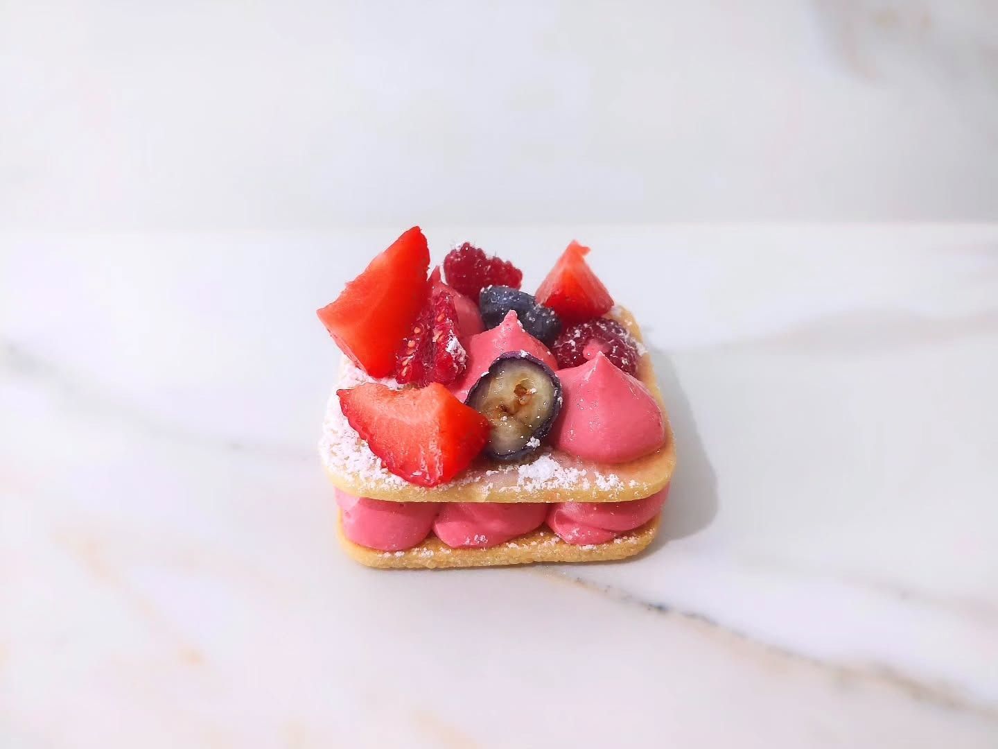 Piccolo dessert: strati di biscotti con crema rosa e frutti di bosco misti.