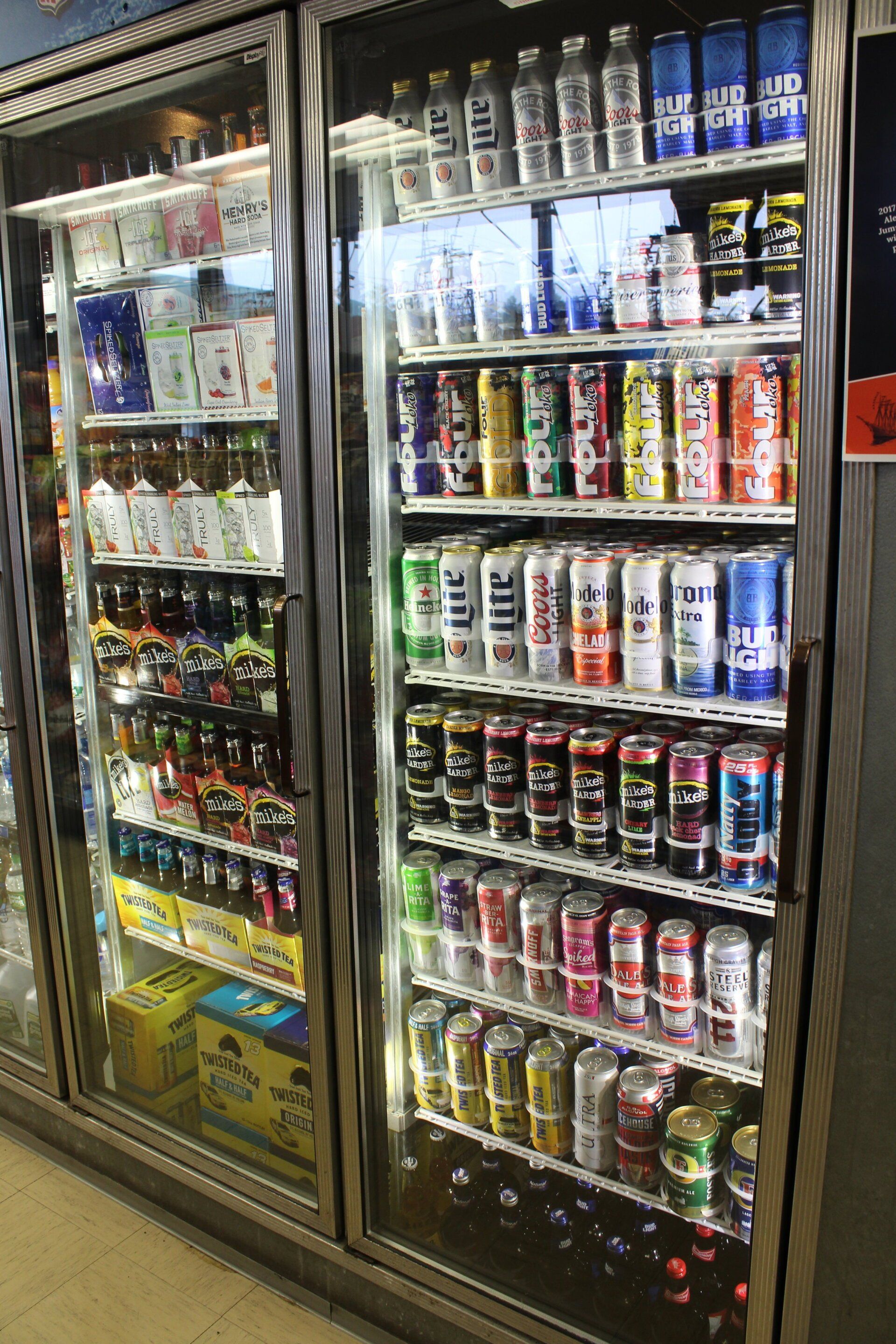A refrigerator filled with lots of cans and bottles of soda.