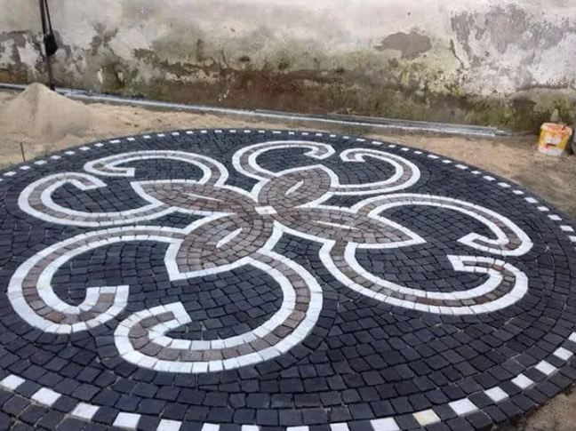 Interno di uno spazio moderno con opere d'arte e un bancone in legno, illuminato da luci sospese, pareti scure.