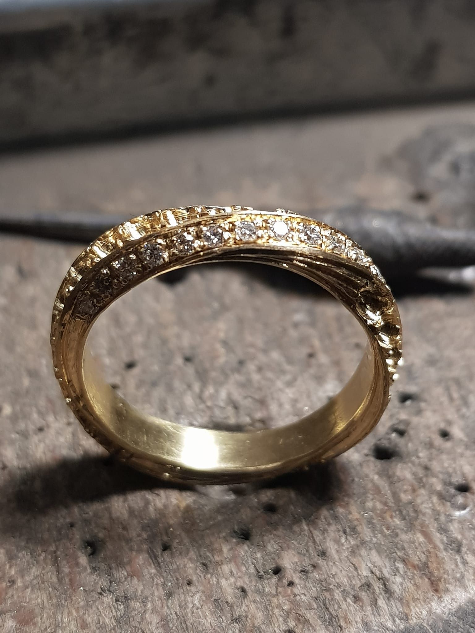Anello in oro con fascia testurizzata, piccoli diamanti su superficie testurizzata.