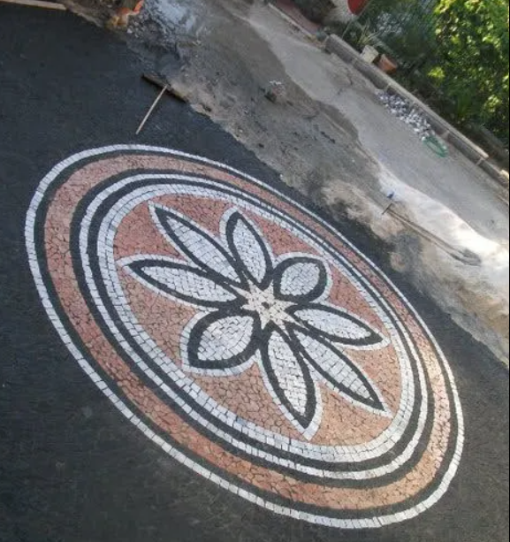 Collana in oro con motivo a foglia e pendente a forma di perla a goccia su una foglia verde.