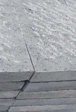 Due fedi nuziali in oro rosa testurizzato poggiano su legno galleggiante.