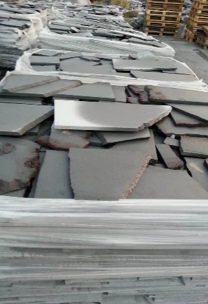 Collana con ciondolo in oro con superficie testurizzata e piccole gemme su sfondo in legno.