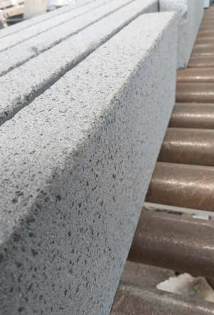 Anello in oro con una fila di gemme verdi e blu, esposto su un supporto bianco all'interno di una scatola.