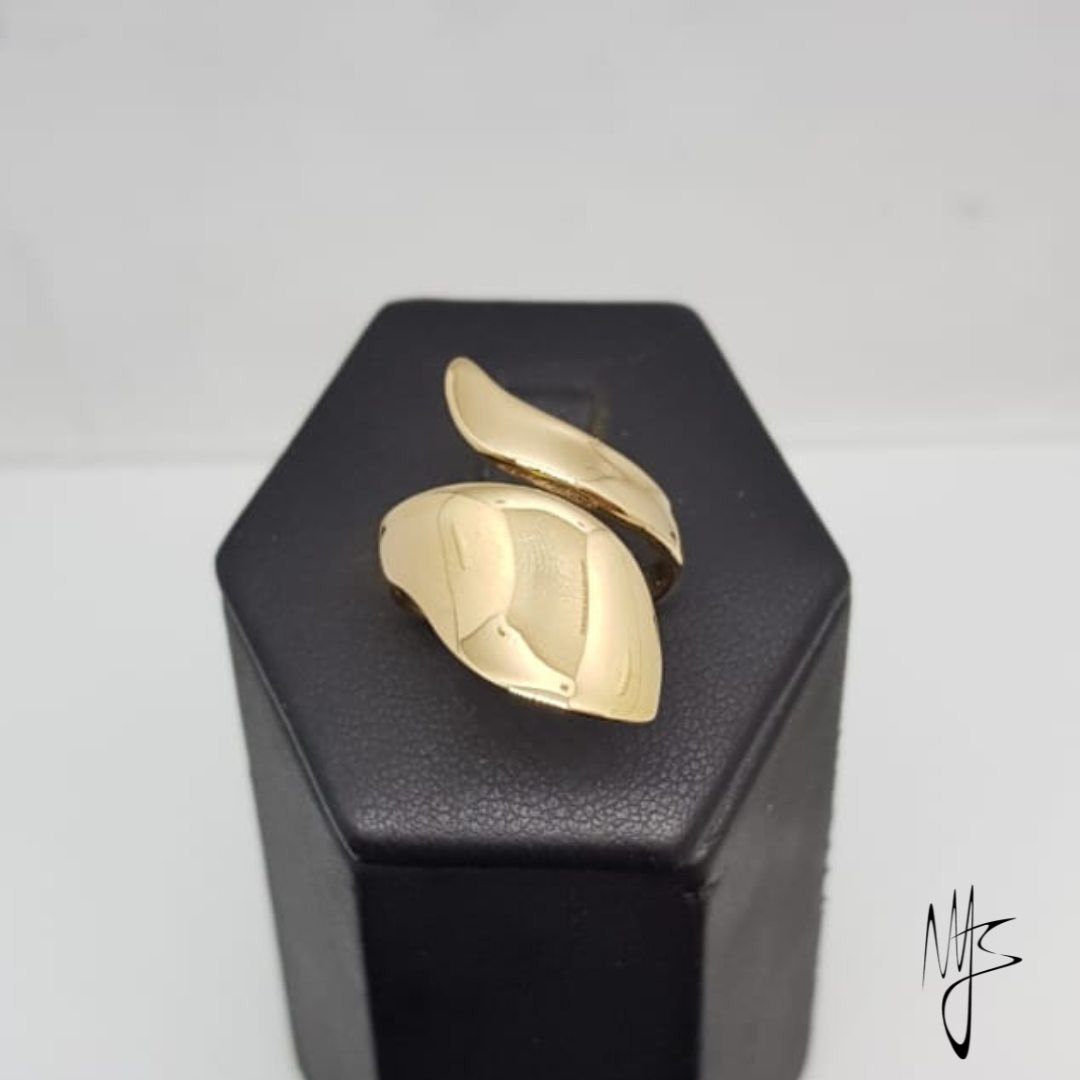 Anello avvolgente color oro esposto su un supporto nero su sfondo bianco.