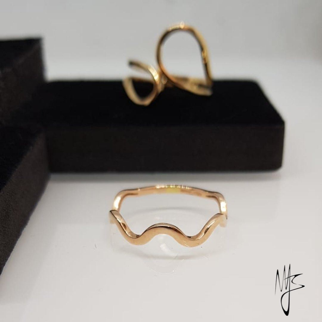 Due anelli d'oro su una scatola nera, un anello ondulato davanti e un anello aperto dietro.