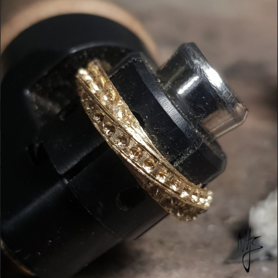 Anello d'oro in uno strumento da gioielliere nero, pronto per la riparazione o la finitura.