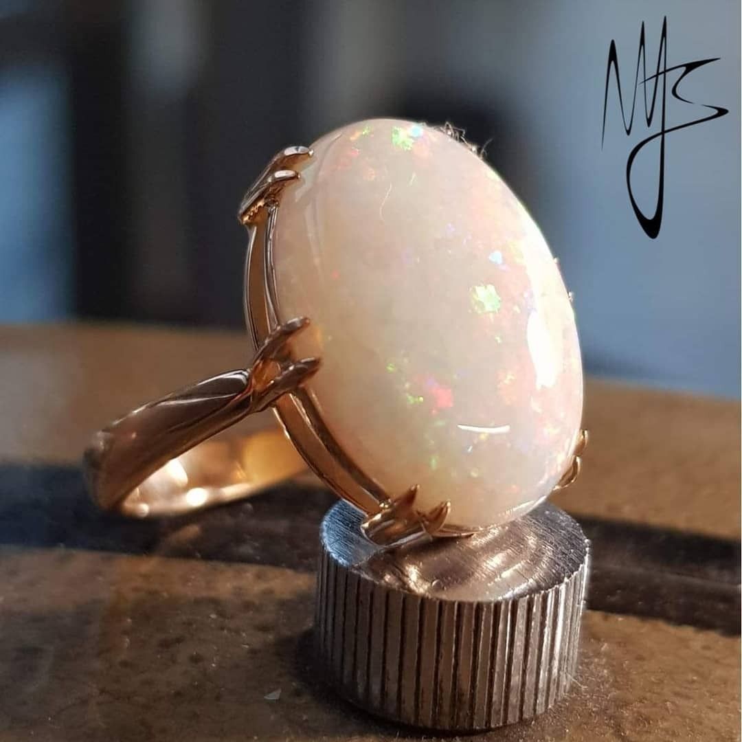 Anello in oro con grande pietra preziosa ovale di opale, incastonata su un supporto in argento.
