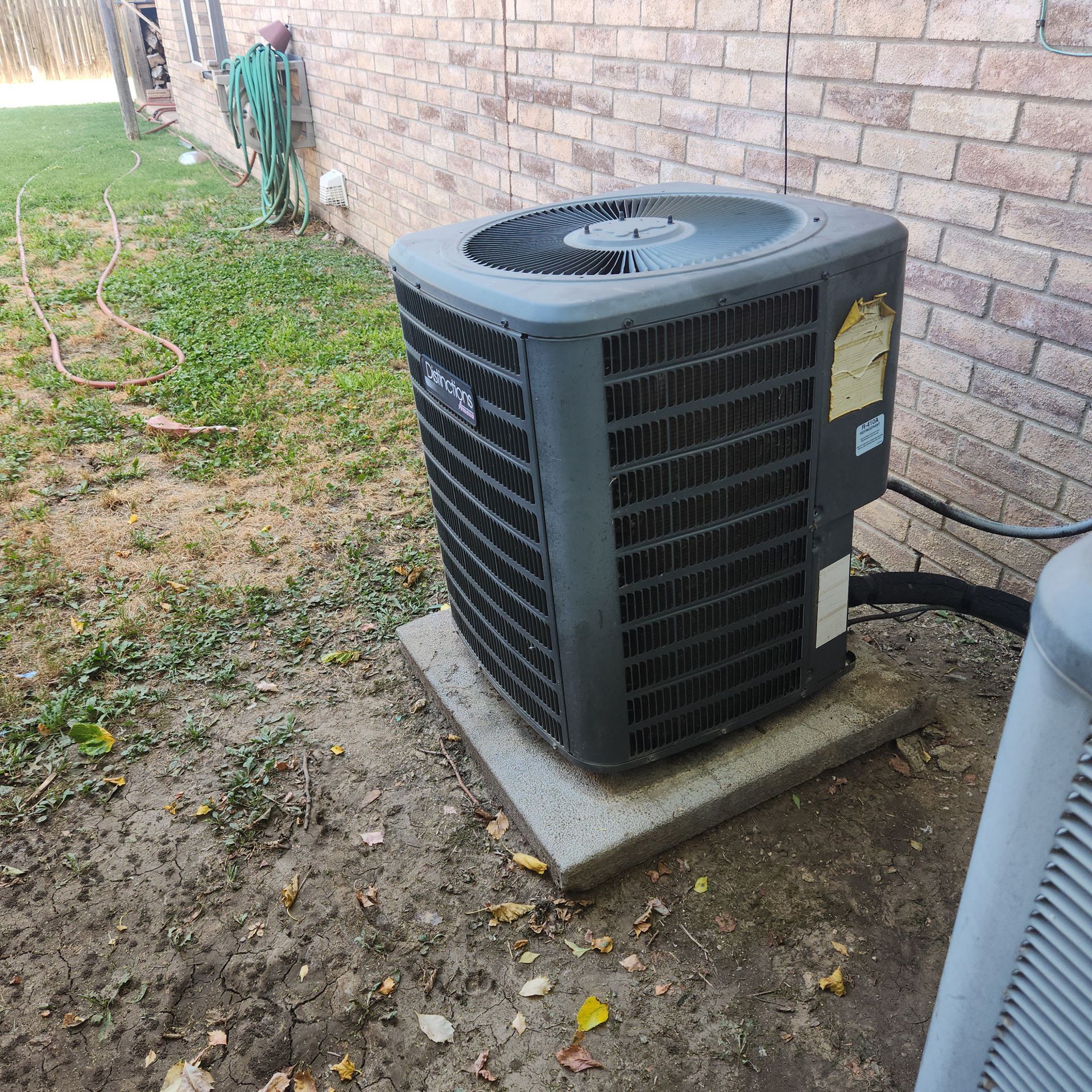 An air conditioner is sitting outside of a brick building.