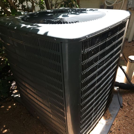 A large air conditioner is sitting on the ground outside