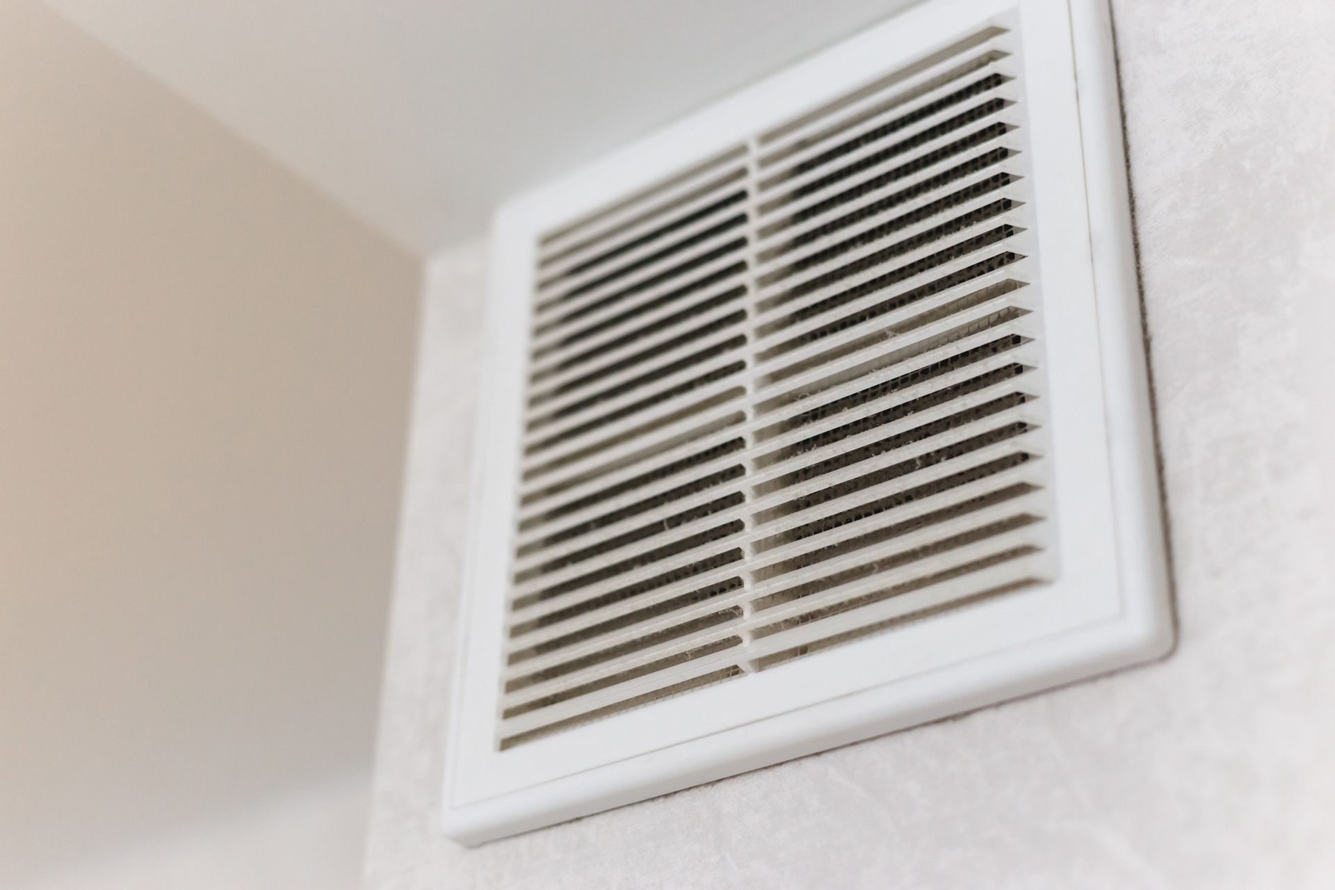 A close up of a white air vent on a wall.