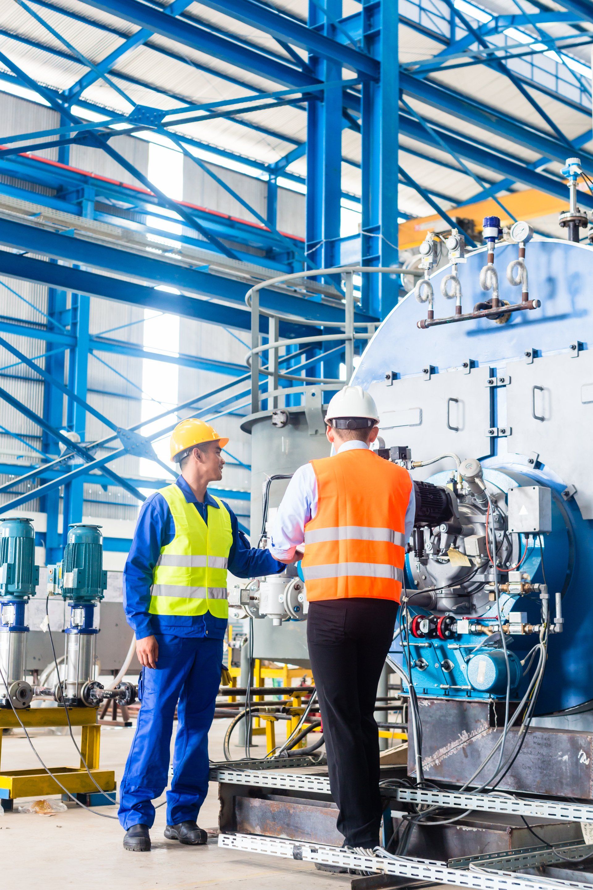 Two men are working on a machine in a factory.