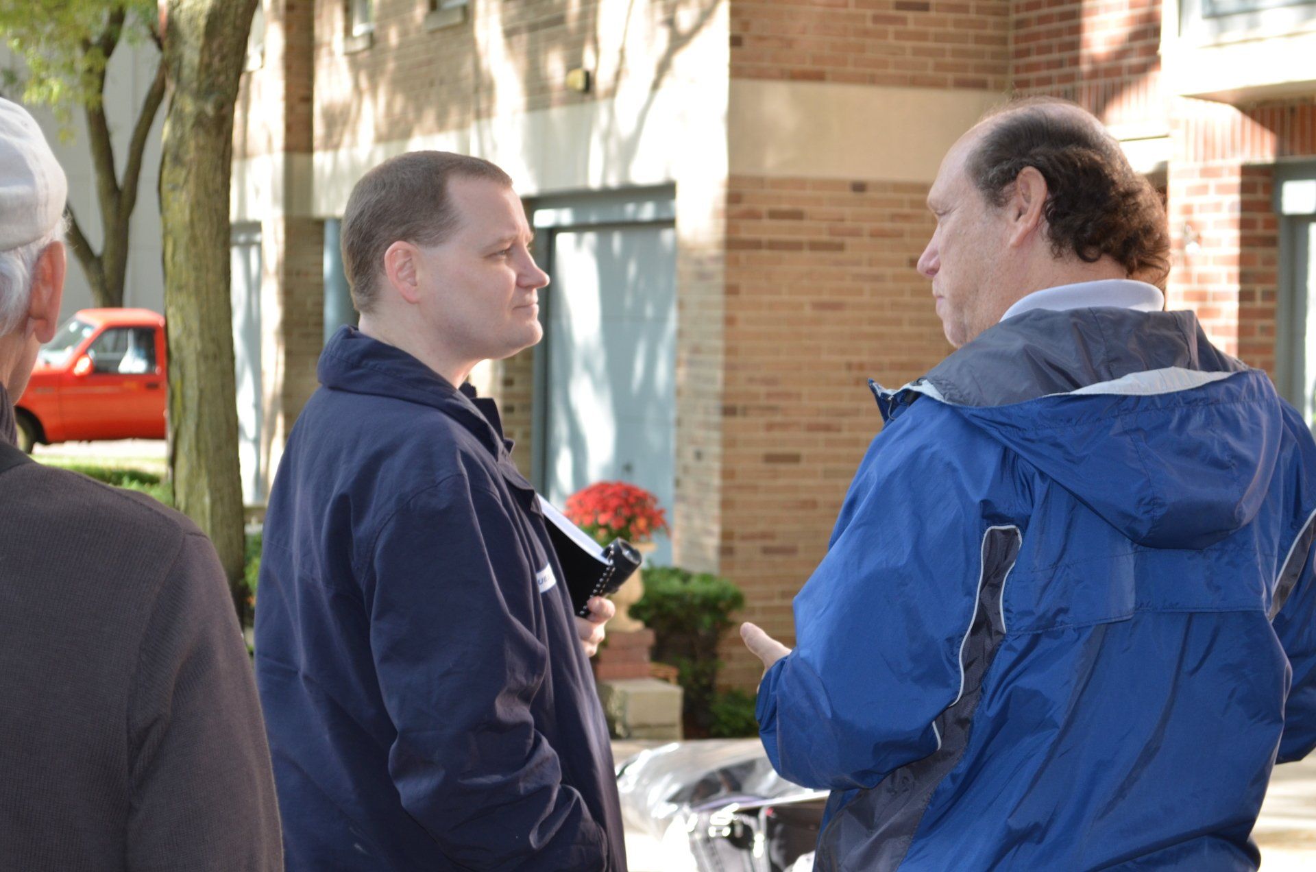 A man in a blue jacket is talking to another man