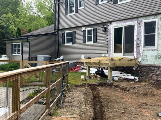 Wooden deck under construction with staircase, next to a building with windows.