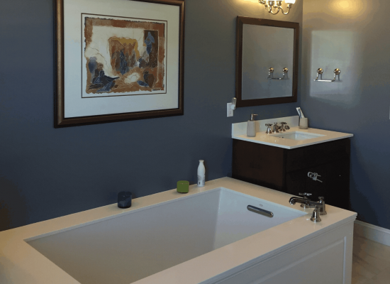 Modern bathroom with a white bathtub, dark blue walls, and a framed artwork.