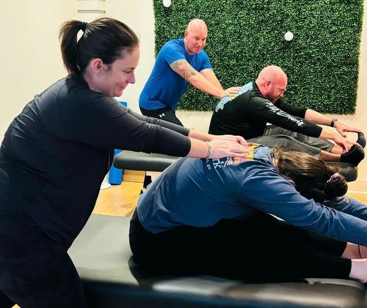 A group of people are doing stretching exercises in a gym.