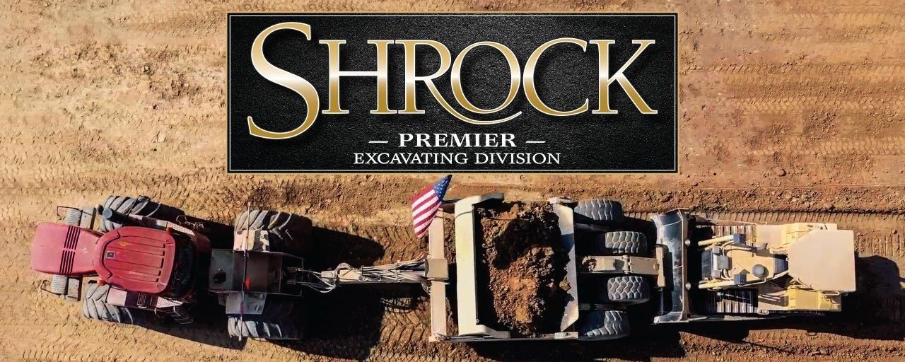 An aerial view of a construction site with the Shrock Premier Excavating Division logo in the foreground. 