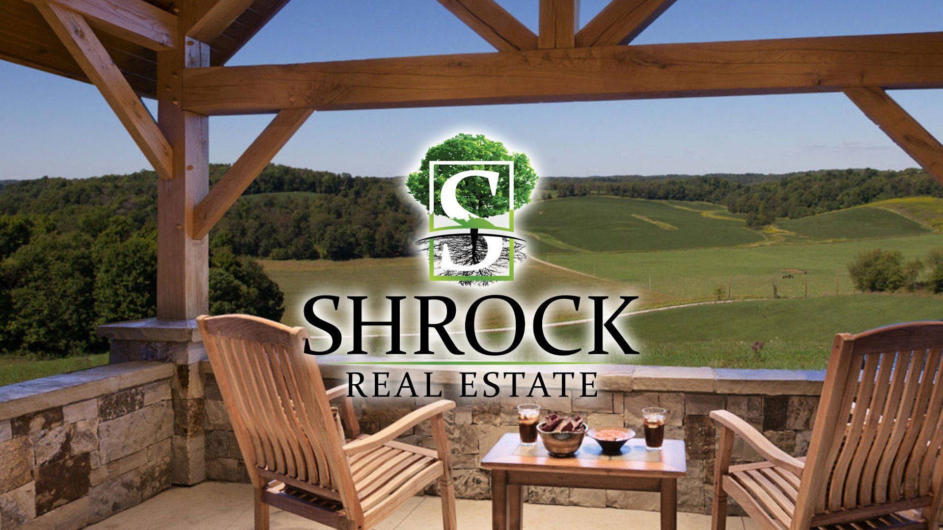 Two chairs and a table on a balcony with the Shrock Real estate logo in the foreground. 