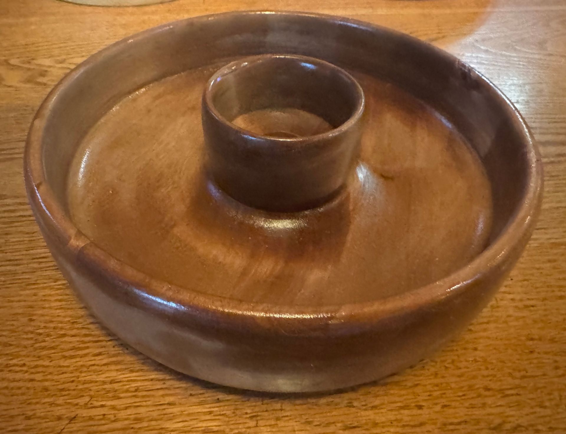 Brown ceramic cheese and cracker server on a wooden table.