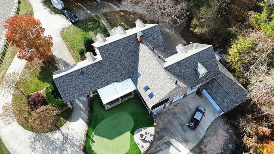 An aerial view of a house with a golf course in the backyard.
